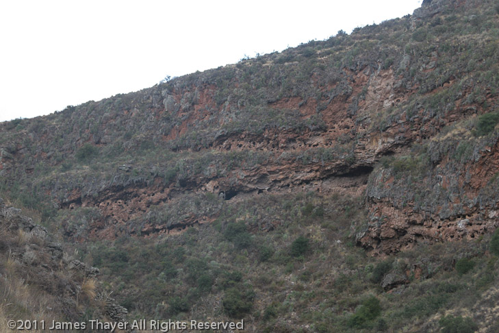 The holes are Incan tombs. Unfortunately, they have been looted by huaqueros (grave robbers).